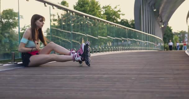Hosszú Hajú Lány Görkorcsolyát Visel Hídon Háttal Áll Üvegkorlátnak Egy — Stock videók