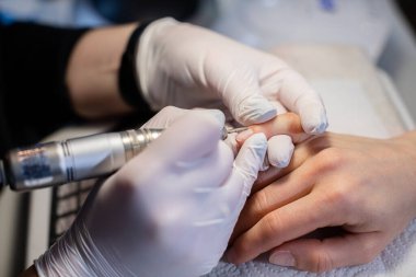 Güzellik uzmanı tırnak bakımı için tırnak tabağı hazırlıyor. Güzellik salonunda manikür makinesi kullanmak. Güzellik tedavileri için profesyonel ekipman.