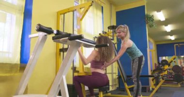 Bir kadın, özel ekipman konusunda kadın eğitmene bahşiş verir. Bir kız spor hocasının profesyonel yardımını dinler..