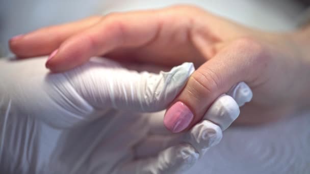 美容师把客户的指甲涂成粉红色 粉红大拇指钉一个女人的手 有漆过的钉子用一次性氮肥手套工作 — 图库视频影像