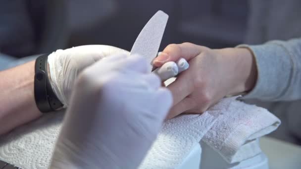一个戴着乳胶手套的美容师锯下了客户的指甲 客户有天然的短指甲 在美容院工作体验美容疗法 — 图库视频影像