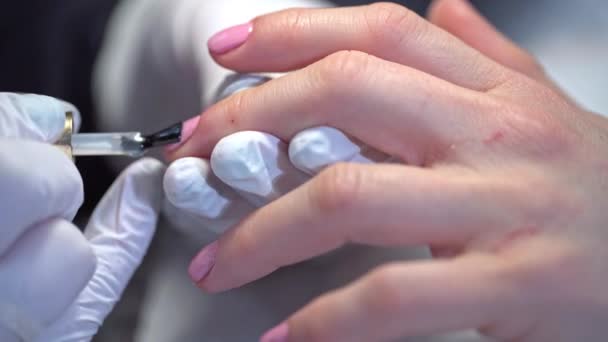 美容师在客户的指甲上涂上一个清晰的顶盖 在美容院画指甲钉硬化剂涂在粉红抛光物上 修指甲用修指甲处理过的天然指甲板 — 图库视频影像