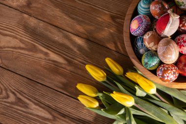 Elle boyanmış Paskalya yumurtaları ahşap bir kasede üst üste istiflenmiş. Paskalya süslemesi kendi kompozisyonun veya grafik yazıtların için bir temel olarak.