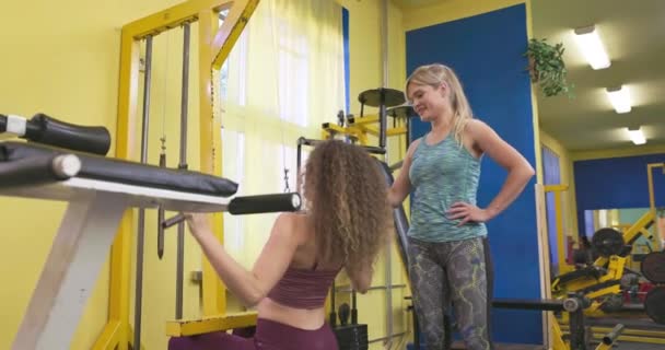運動トレーナーの助けを借りて 機器の演習の女性 パーソナルトレーナーは 彼女の腕のワークアウトと軽薄な髪の女性を助ける — ストック動画