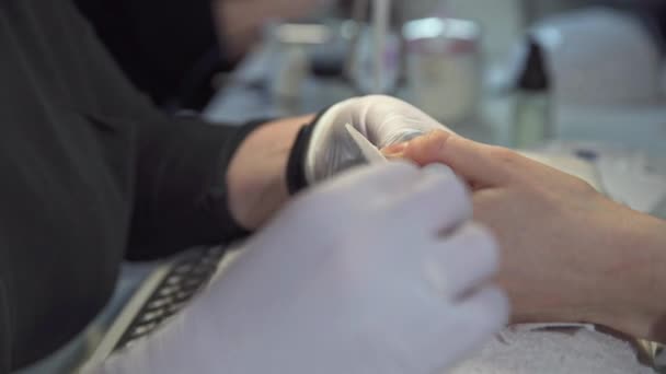 在美容院工作的美容师的近照 一个戴着胶乳手套的员工牵着客户的手 那个女人正在用文件锯指甲 — 图库视频影像
