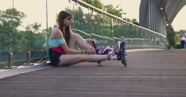 Das Langhaarige Mädchen Trägt Rollerblades Sie Sitzt Auf Der Brücke — Stockvideo