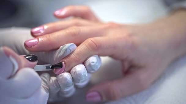 把光泽涂在涂有粉红抛光的钉子上 美人鱼对指甲的影响由专业人士进行 美容师在美容院给顾客画指甲 — 图库视频影像