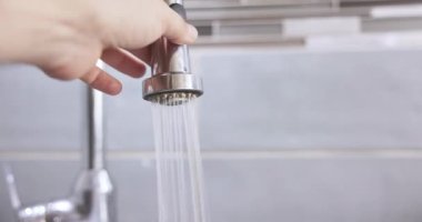 Biri musluktaki bir düğmeye basıyor. Musluk suyunun akışını değiştirmek.