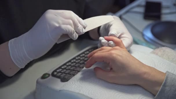一个戴乳胶手套的女人会锯下客户的指甲 工作在一个天然的钉子板 一个女人剪掉她客户的指甲 参观一个现代美容院 — 图库视频影像