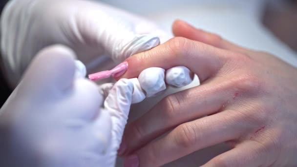 画食指的指甲 一个女人在美容院接受治疗时的特写镜头 用粉红指甲油美容院深层美容美发服务 — 图库视频影像