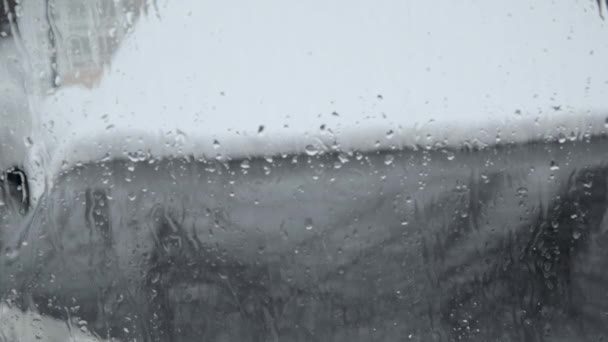 水のストレッチは ウィンドウを滴下 フロントガラスを通して見られるように雪が降る 外の悪天候 ガラスの上に水滴が沈んでいる ガラス越しに見えるのは — ストック動画