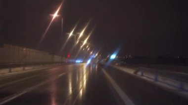 Yolcu vagonunun ön camından bak. Gece vakti şehrin içinden geçerek. Araba düz bir yolda gidiyor. Bulanık sokak lambalarını, sokak levhalarını ve bilgi panolarını geçiyor.