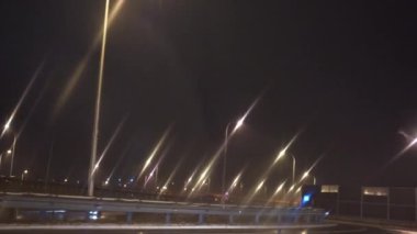 Yolcu vagonunun ön camından bak. Islak, kaygan bir sokakta, şehirde araba sürmek. Araba asfalt bir yol boyunca ilerliyor. Bir sokak lambasının bulanık ışıkları.