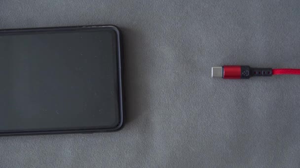 将微型Usb插头插入电话插座 带红线的充电器桌上放着黑屏手机 关掉了手机 将微型Usb插头插入电话 — 图库视频影像