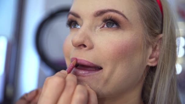 Kosmetyczka Rysuje Kontur Ust Klienta Kładąc Dłonie Twarzy Klienta Młoda — Wideo stockowe