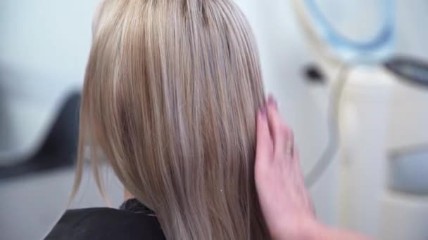 大櫛でクライアントの髪を結合美容師 後ろから見たブロンドの髪の頭 ブロンドの髪の女性のバックビュー 美容治療のための髪の準備 — ストック動画