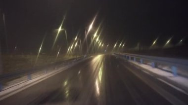 Yolcu vagonunun ön camından bak. Buz gibi kaygan bir sokakta, şehirde araba sürmek. Araba asfalt bir yol boyunca ilerliyor. Araç sokak lambalarını ve trafik işaretlerini geçiyor.
