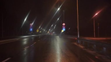 Bir yolcu aracının sürücüsü geceleyin asfalt bir yolda seyahat ediyor. Kötü hava koşulları ve araba sürerken görüş mesafesi zayıf. Sürücü perspektifinden sokağa bak.