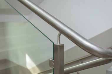 Merdiven elementi. Paslanmaz çelik bir direğe ve güçlendirilmiş cam levhaya bağlı bir merdiven parçası..