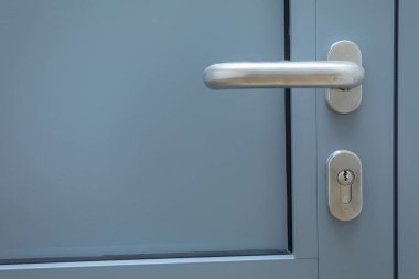 Gri alüminyum kapı çelik renkli metal saplı ve kilit silindirli. Seçili bileşenlerin yakın görüntüsü.