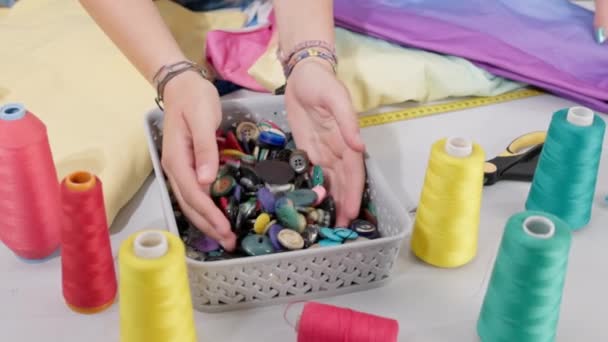 塑料篮子里的裁缝店桌上放着许多不同尺寸的彩色钮扣 裁缝店里摆满了小饰物 — 图库视频影像