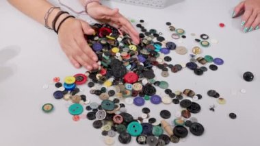 Uygun düğme rengini seçtikten sonra, diğerleri masadan plastik bir kabın içine toplanır. Terzi dükkanları.