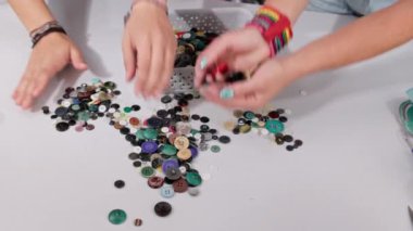 Uygun düğme rengini seçtikten sonra, diğerleri masadan plastik bir kabın içine toplanır. Terzi dükkanları.