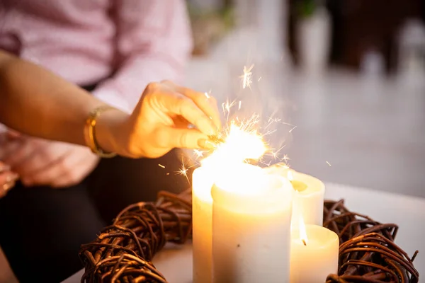 stock image Four lit candles stand on the table as decoration and from them the girl lights fireworks. Romantic mood with burning candles.