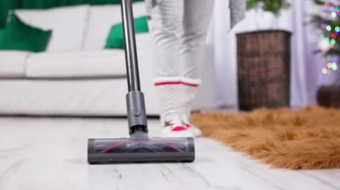Evin zeminini elektrikli süpürgeyle temizlerken çekilmiş yakın plan bir fotoğraf. Ev hizmetleri, davetlilerin eve gelişinden önce devam ediyor..