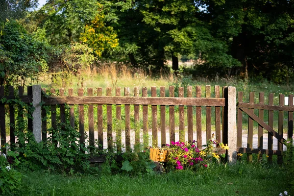 stock image A rural old fence, bathed in the rays of the setting sun. Summer season in rural views.