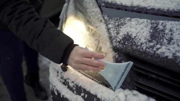 Person Shoveling Snow Her Car Scraper She Scrapes Lights Her — стокове відео