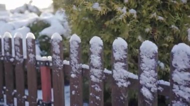 Close-up of the fence. The fence of the house on a winter day. The fence is covered with fresh snow. There is a thick layer of ice on the top of the fence in some places.