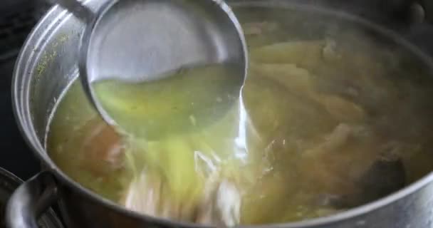 锅子里的肉汤是煮沸的 锅子的密闭部分 把一个勺子蘸到汤里搅拌好几次 用皮肤从肉汤中取出脂肪鸡 — 图库视频影像