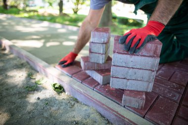 İşçi elle kaldırım taşlarını düzleştirilmiş ve sıkıştırılmış bir yüzeye serer. Ağır ve zahmetli inşaat işi.