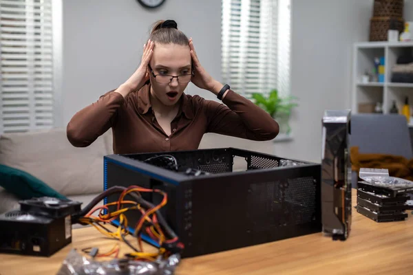 女性は壊れたコンピュータを修正する方法を不思議に思います 彼女はテーブルに座り コンピュータはカウンターに横たわっている 女性は彼女の口を開いて 彼女の手で彼女の頭を保持しています — ストック写真