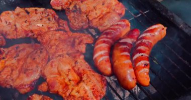 Izgarada kızartılmış sosis ve domuz eti yakın çekim. Sigara, sıcak hava ve yaz mevsimi lezzetli yemekler için bir reçetedir..