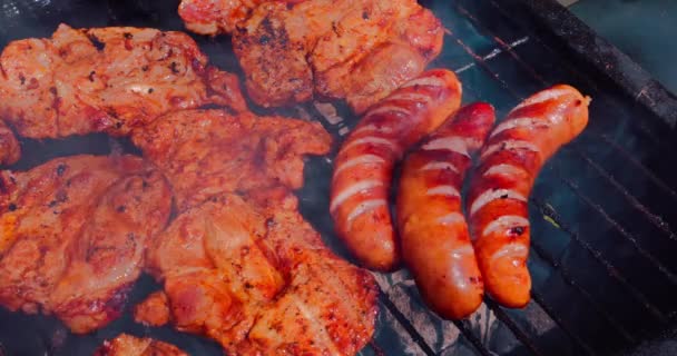 一个特写镜头烤香肠和猪肉在热烤架上 烟熏热的空气和夏天是好吃的食物的配方 — 图库视频影像