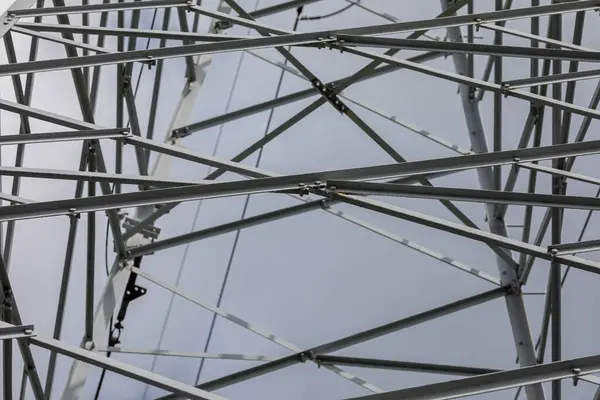 Close-up view of the steel truss of a high-voltage line pole. Miles of steel angles connected in an orderly fashion to maintain stability and strength.
