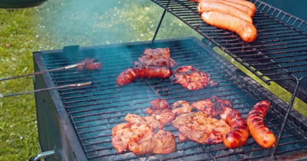 男性は茶色の肉を舌で緑の皿に移しました 夏季のホットグリルグレートで豚肉のベークの厚いスライス — ストック動画