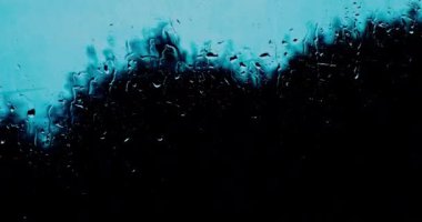 Akşamları bulutlu ve yağmurlu bir günde, arabanın ön camında akan su ve yağmur damlaları görülebilir..