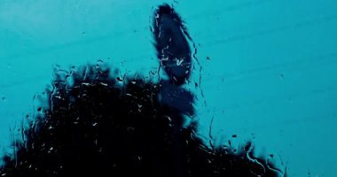 Akşamları bulutlu ve yağmurlu bir günde, arabanın ön camında akan su ve yağmur damlaları görülebilir..