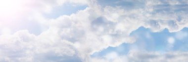 Güneşin keskin ve beyaz bir şekilde parladığı uzamış bir gökyüzü çerçevesi. Bulutlarla kaplı mavi gökyüzünün doğal bir görüntüsü.