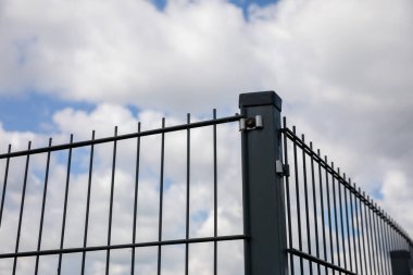 Üzerinde çit panelleri olan bir köşe çiti manzarası. Arka planda beyaz bulutlu mavi bir gökyüzü.