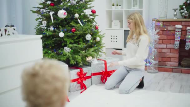 Een Blonde Vrouw Knielt Bij Een Kerstboom Een Jongetje Rent — Stockvideo