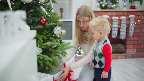 Egy Szőke Szemüvegben Egy Karácsonyfa Mellett Mellette Egy Kisfiú Áll — Stock videók
