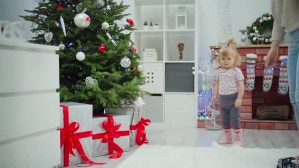 Egy Kislány Odasétál Egy Díszített Karácsonyfához Amely Alatt Nagy Ajándékok — Stock videók