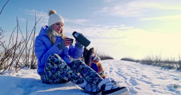 Молода Блондинка Одягнена Теплу Куртку Кепку Сидить Снігу Наливає Собі — стокове відео