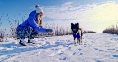 Sarışın bir kadının küçük tüylü bir köpeği var. O, onunla bir yürüyüş için dışarı çıkar. Dışarısı buz gibi ve kar var. Kadın bir avuç dolusu kar fırlattı. Köpek onun yanına oturur..