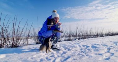 Bir kadın ve köpeği vahşi doğada yürüyüşe çıktılar. Sahibi karda köpeğiyle oynuyordu. Köpek iyi huylu ve tasmasız yürüyebiliyor..