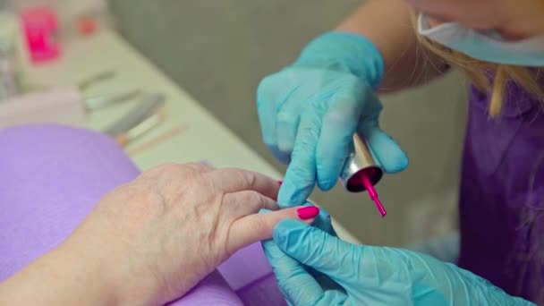 美容院で働く女性は クライアントの爪を塗ります ポーランド語を適用しながら 美容師は木製の棒で治具を押し戻します — ストック動画